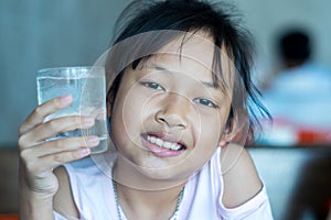 Smile asian child girl hold a glass of ice water