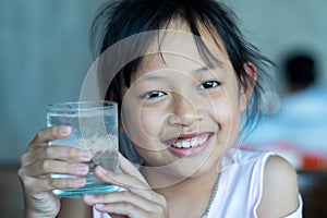 Smile asian child girl hold a glass of ice water