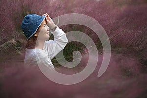 smile Asian young woman hold hat brim at hairawn muhly grass