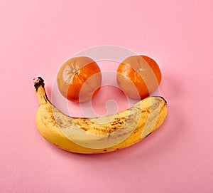 Smile of banana and tangerines on a pink background