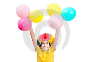 Smile boy in clown wig holds hands up with balloons