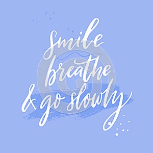 Smile, breathe and go slowly. Inspirational quote about calmness, mindfulness and slow life. White handwritten text on