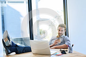 Smile, business man and work on laptop in desk at office in startup company as architect. Entrepreneur, feet on table