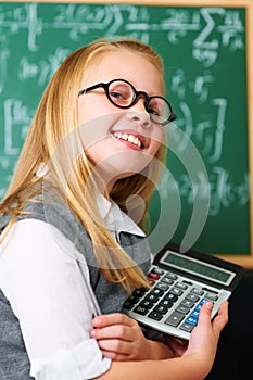 Smile, calculator and child student in classroom for mathematics homework, lesson or test. Learning, education and
