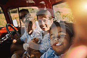 Smile for the camera mom and dad. a cheerful young family driving in a red pickup truck on a rural road while taking a