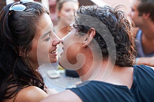 Smile, couple and kiss at cafe with friends for bonding, love and weekend fun. Happy, affection and young man and woman
