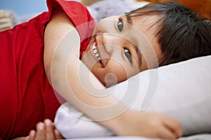 Smile, cute and boy child on bed playing and having fun at home with positive, good and happy attitude. Laughing, funny