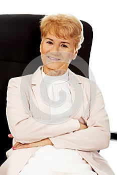 Smile elderly business woman sitting on armchair