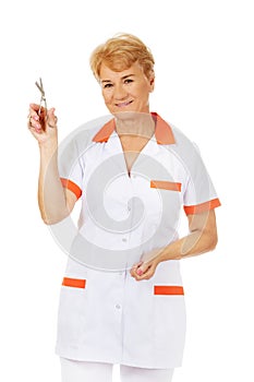 Smile elderly female doctor or nurse holding scissors