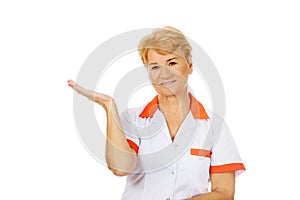 Smile elderly female doctor or nurse preseting something on open palm