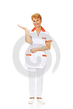 Smile elderly female doctor or nurse preseting something on open palm