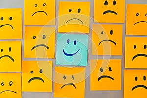 smile face sticky note surrounded by sad face stickynote photo