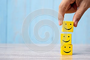 Smile face on yellow wood cube. Service rating, ranking, customer review, satisfaction and emotion concept