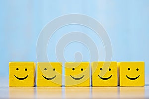 Smile face on yellow wood cube. Service rating, ranking, customer review, satisfaction and emotion concept
