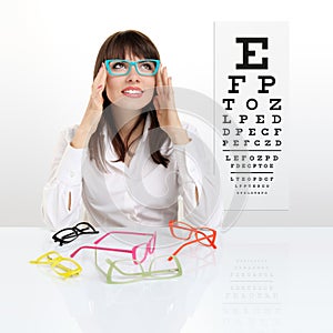 Smile female face chooses spectacles on eyesight test chart back