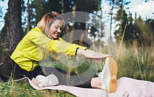 Smile girl exercising outdoors in green park, activity with stretch arms and legs. Happy fitness woman doing stretching exercises