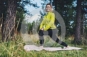 Smile girl exercising outdoors in green park, activity with stretch legs. Young fitness woman doing stretching exercises training