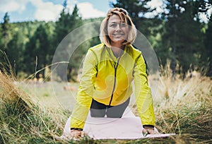 Smile girl exercising outdoors in green park, activity young fitness woman doing stretching exercises training outside