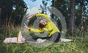 Smile girl exercising outdoors. Young fit woman doing stretching exercises  training outside in green park. Sport woman play yoga