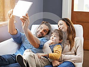 Smile. a happy family using a digital tablet to take a selfie.