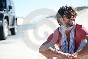 Smile, happy man sitting in desert and road trip with freedom, car travel and adventure for summer vacation. Transport
