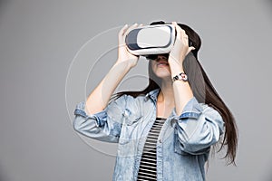 Smile happy woman getting experience using VR-headset glasses of virtual reality on gray background