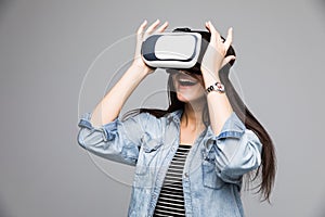 Smile happy woman getting experience using VR-headset glasses of virtual reality on gray background