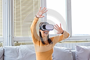 Smile happy woman getting experience using VR headset glasses of virtual reality at home much gesticulating hands. Young woman