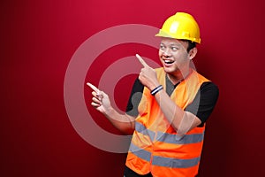 Smile and happy young asian man worker is with with hand point on empty space