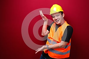 Smile and happy young asian man worker is with with hand point on empty space