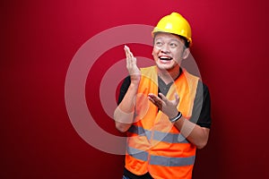 Smile and happy young asian man worker is with with hand point on empty space