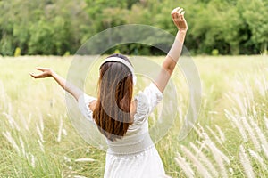 Smile happy young asian woman relaxing and using headphones to listen to music from smart phone in the flower field