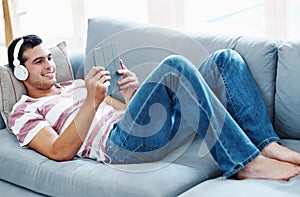 Smile, headphones and man with tablet on sofa for online streaming, video and watching movie. Happy, relax and male