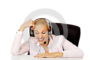 Smile helpline operator sitting behind the desk and talking through a headphones