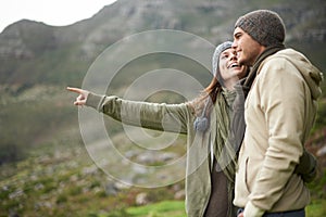 Smile, hiking and pointing with couple in mountains together for love, dating or sightseeing. Travel, environment or