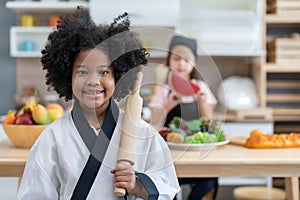 Smile little girl in chef uniform holding rolling pin for preparing to make cake bakery in kitchen