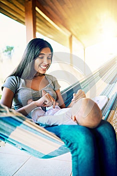 Smile for mommy. a cheerful young mother relaxing on a hammock with her infant son outside at home during the day.