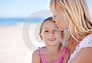 Smile, mother and kiss kid at beach on holiday, summer or love on vacation at sea. Face, mom and happy girl at ocean for