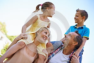 Smile, parents and carrying children in park, shoulders and quality time in nature. Love, fun and joyful with happy