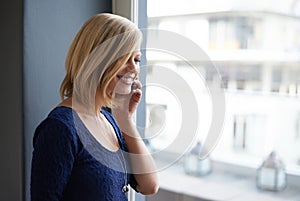 Smile, phone call and woman in home, listening to contact or news by window. Smartphone, chat and happy person in