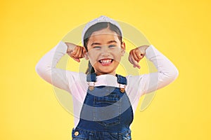 Smile, portrait and girl child with arm flex in studio for confidence, strong and power on yellow background. Happy