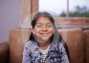 Smile, portrait and girl child on sofa in living room with positive, good and confident attitude. Happy, sweet and face