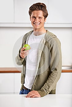 Smile, portrait and man with apple in kitchen of home for diet, health and wellness. Happy, confident and young male