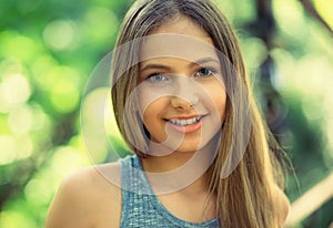 Smile. Portrait of a young beautiful smiling American woman, sunshine girl isolated green outdoors park background