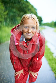 Smile, portrait and young woman in the rain with coat in nature, road or street for winter. Happy, positive attitude and