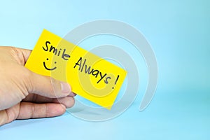 Smile always reminder concept. Hand holding a bright yellow paper message