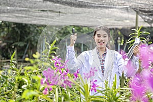 Smile Scientists hold tablets and magnifiers, happy with success. Researcher botanical research orchid wearing Scientist shirt and