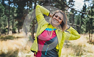 Smile sport girl exercising outdoors in nature. Relaxing activity with stretch arms. Young fit woman doing stretching exercises