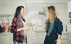 Smile two females drinking milk in the kitchen