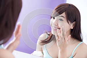 Smile woman applying moisturizer cream